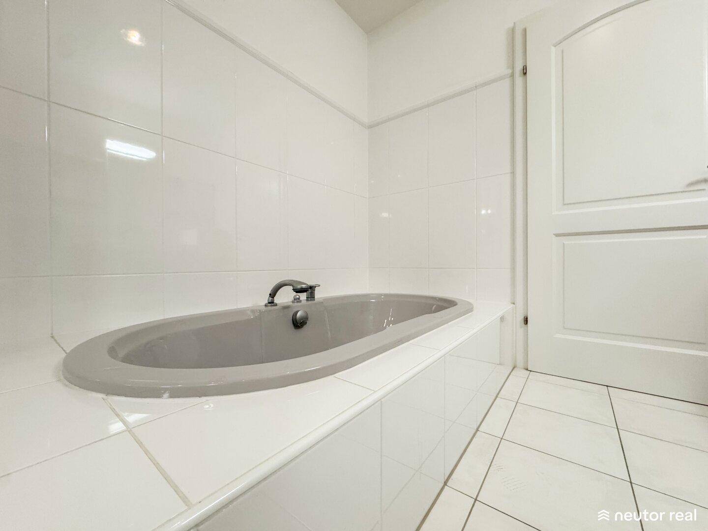 Badezimmer mit einer eingebauten Badewanne und weißen Fliesen, bietet Raum zur Entspannung.