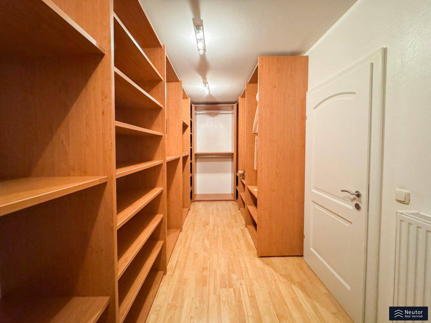 Geräumiger begehbarer Kleiderschrank mit langen Regalen und viel Platz für Kleidung.