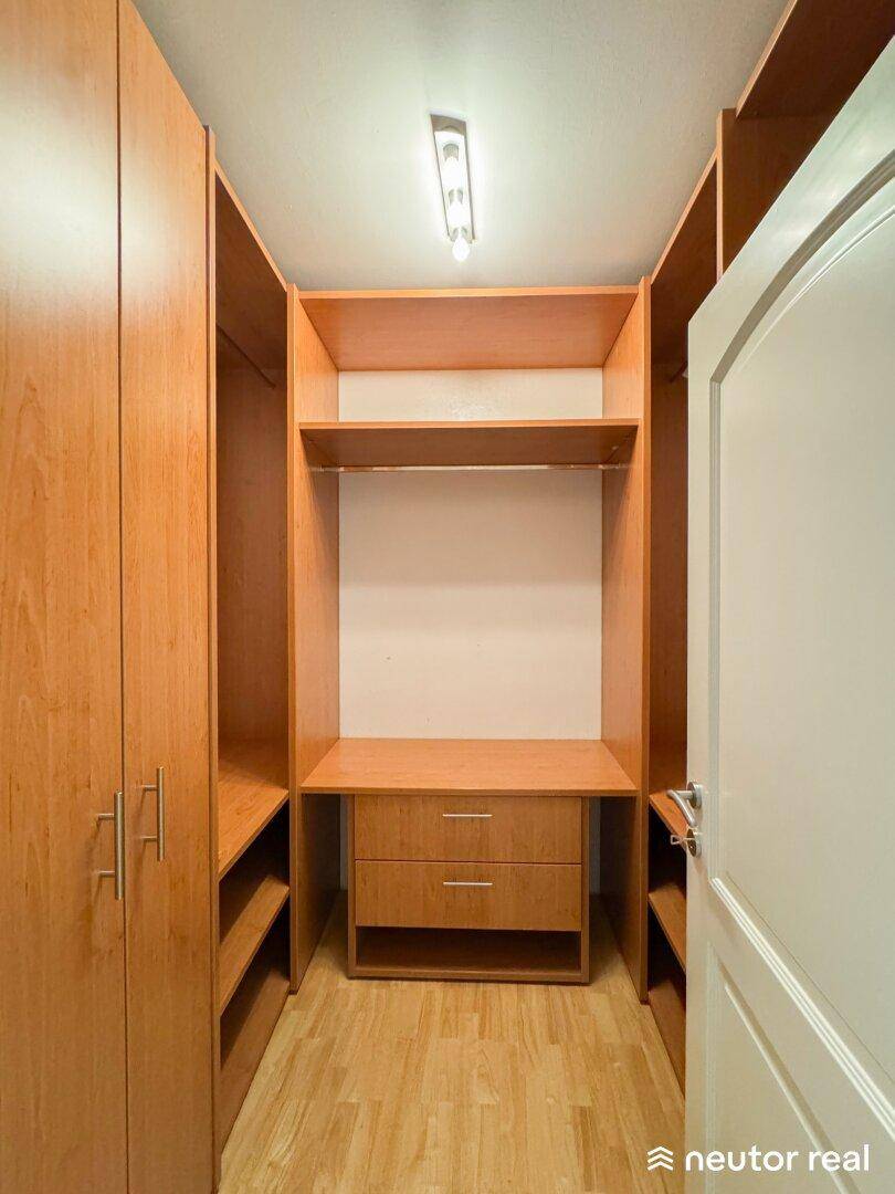 Begehbarer Kleiderschrank mit maßgefertigten Holzregalen und Schubladen, bietet viel Stauraum.