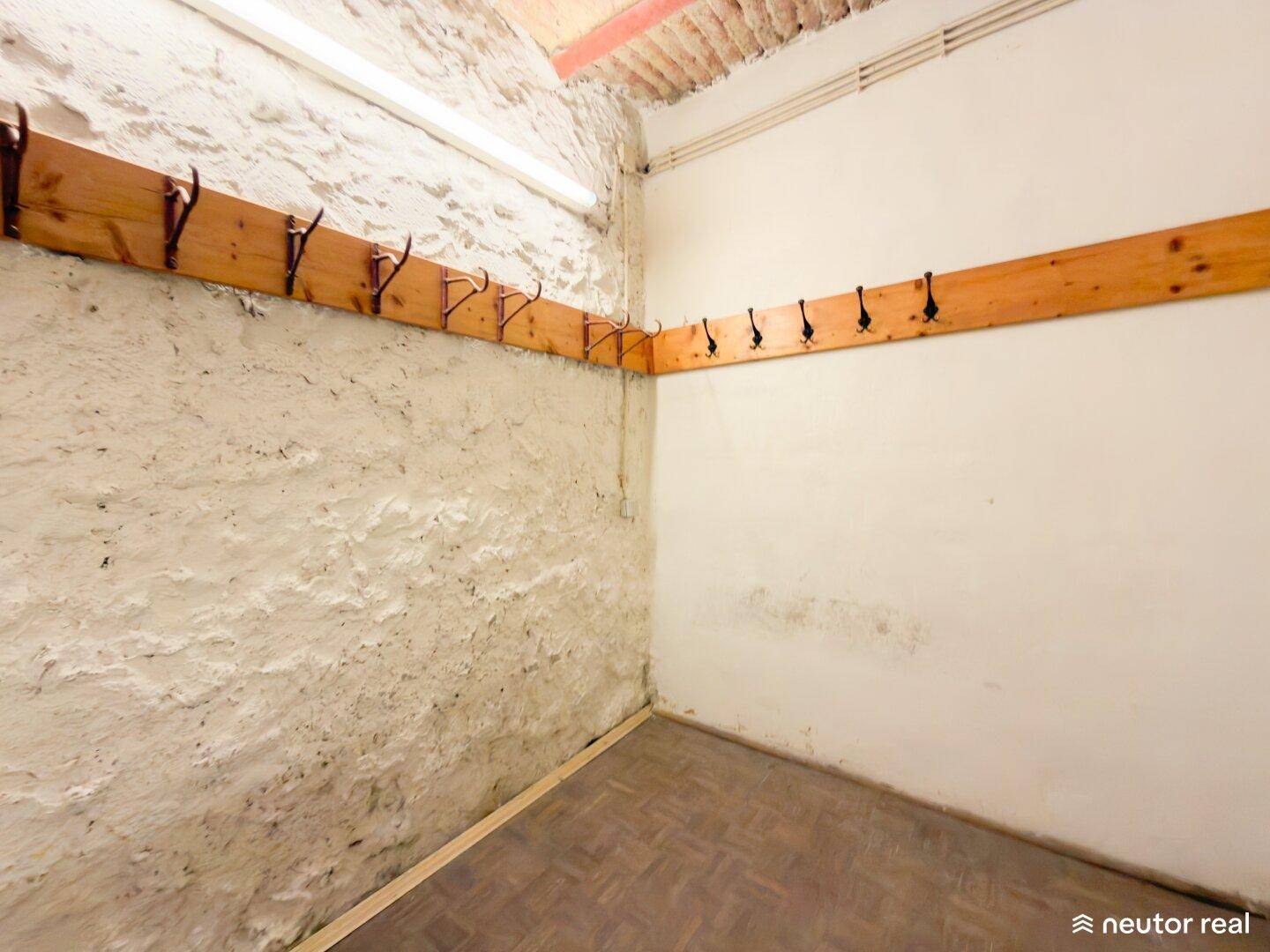 Umkleideraum mit Holzbalken, strukturierten Wänden und einer Reihe von Kleiderhaken.