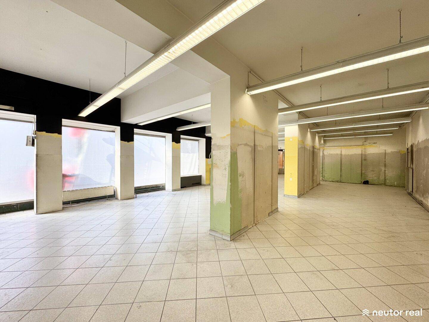 Weitläufiger Gewerberaum mit Säulen, Fliesenboden und großen Fenstern, bereit für eine neue Gestaltung.