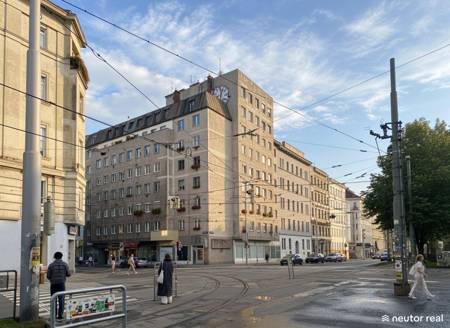 Großes Eckgebäude mit einer Uhr an der Fassade, umgeben von einer belebten Stadtstraße.