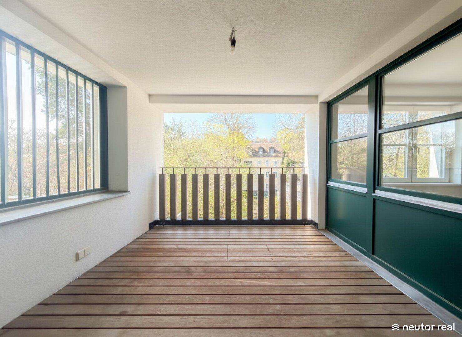 Leere Loggia mit Holzboden und Blick ins Grüne, bereit zur individuellen Gestaltung.