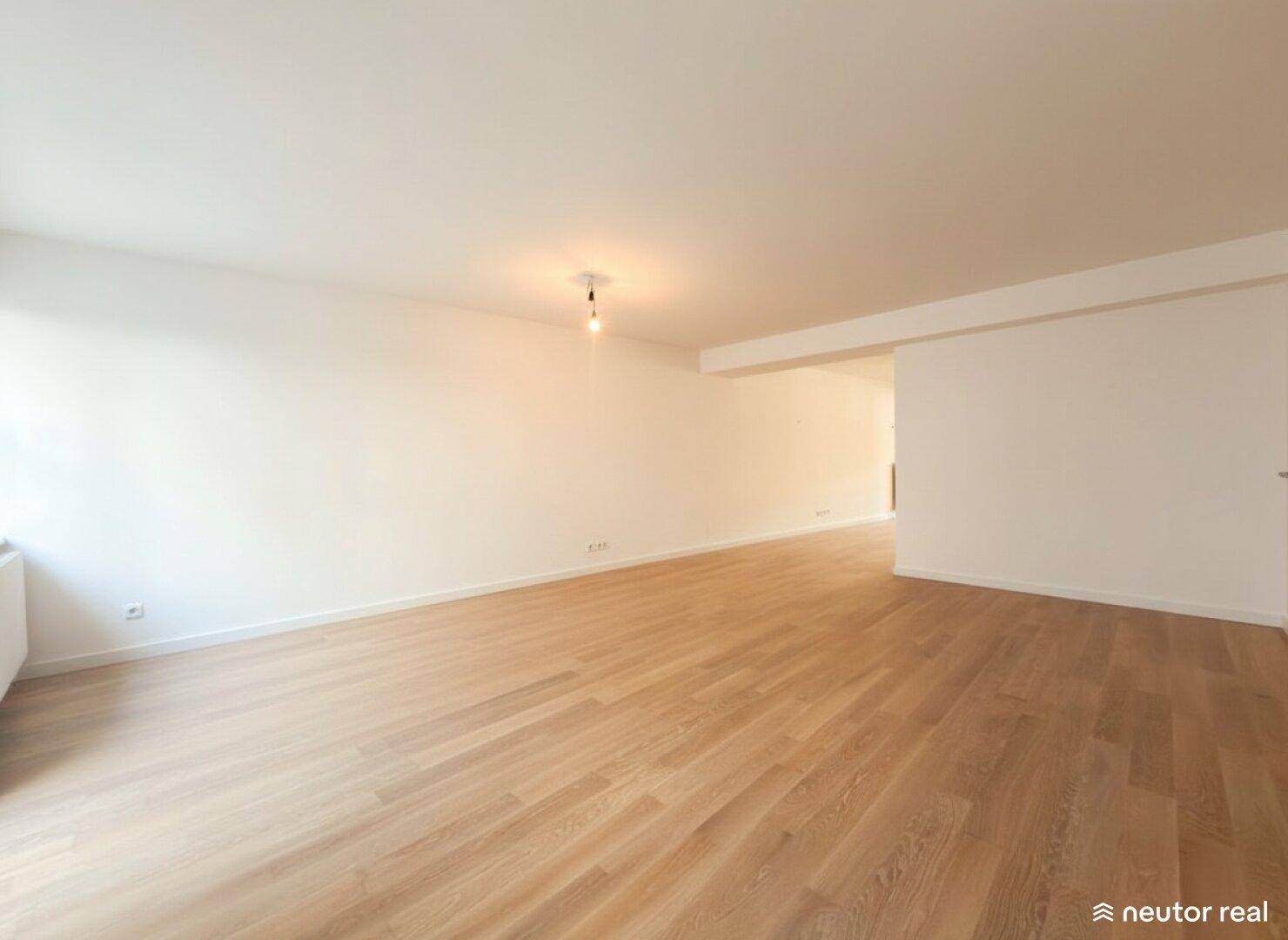 Heller, leerer Raum mit Holzboden und weißen Wänden, ideal für individuelle Gestaltung.