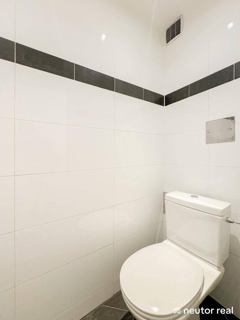 Modernes Gäste-WC mit weißen Fliesen, Wand-WC und Lüftung.