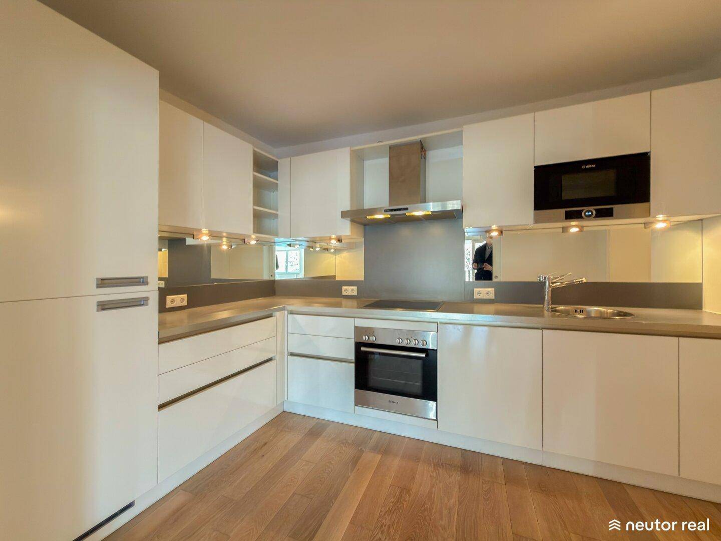 Moderne Einbauküche mit weißen Hochglanzfronten und integrierten Geräten.
