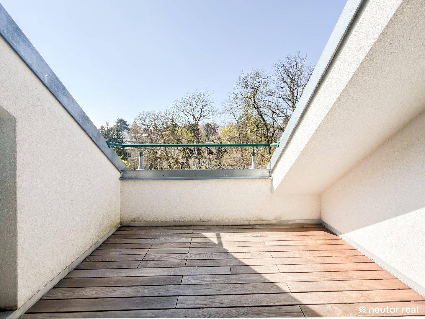 Kleiner Balkon mit Holzfußboden und Blick ins Grüne.