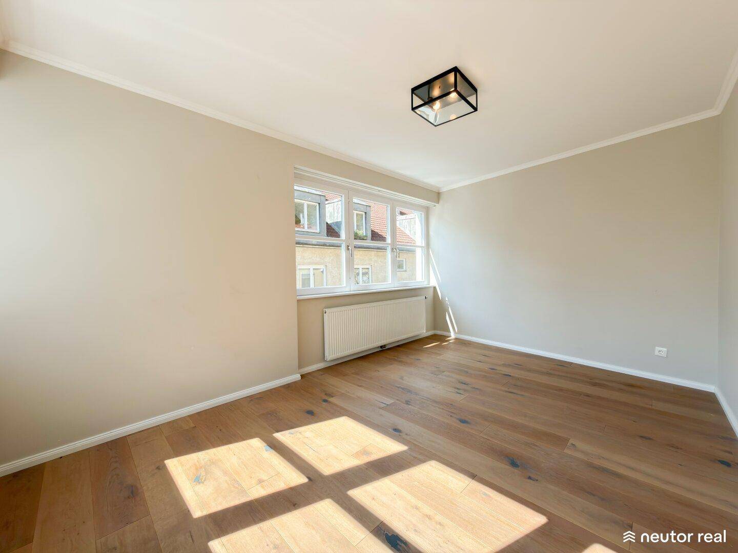 Helles Zimmer mit Holzboden und großem Fenster, bietet vielseitige Nutzungsmöglichkeiten.