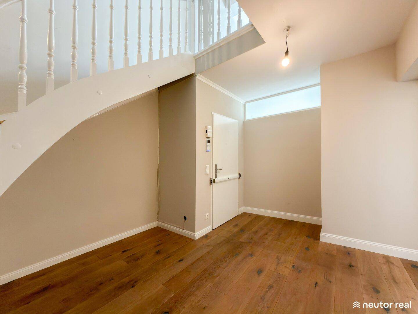 Geräumiger Eingangsbereich mit Holzfußboden und einer eleganten Treppe, die in die oberen Etagen führt.