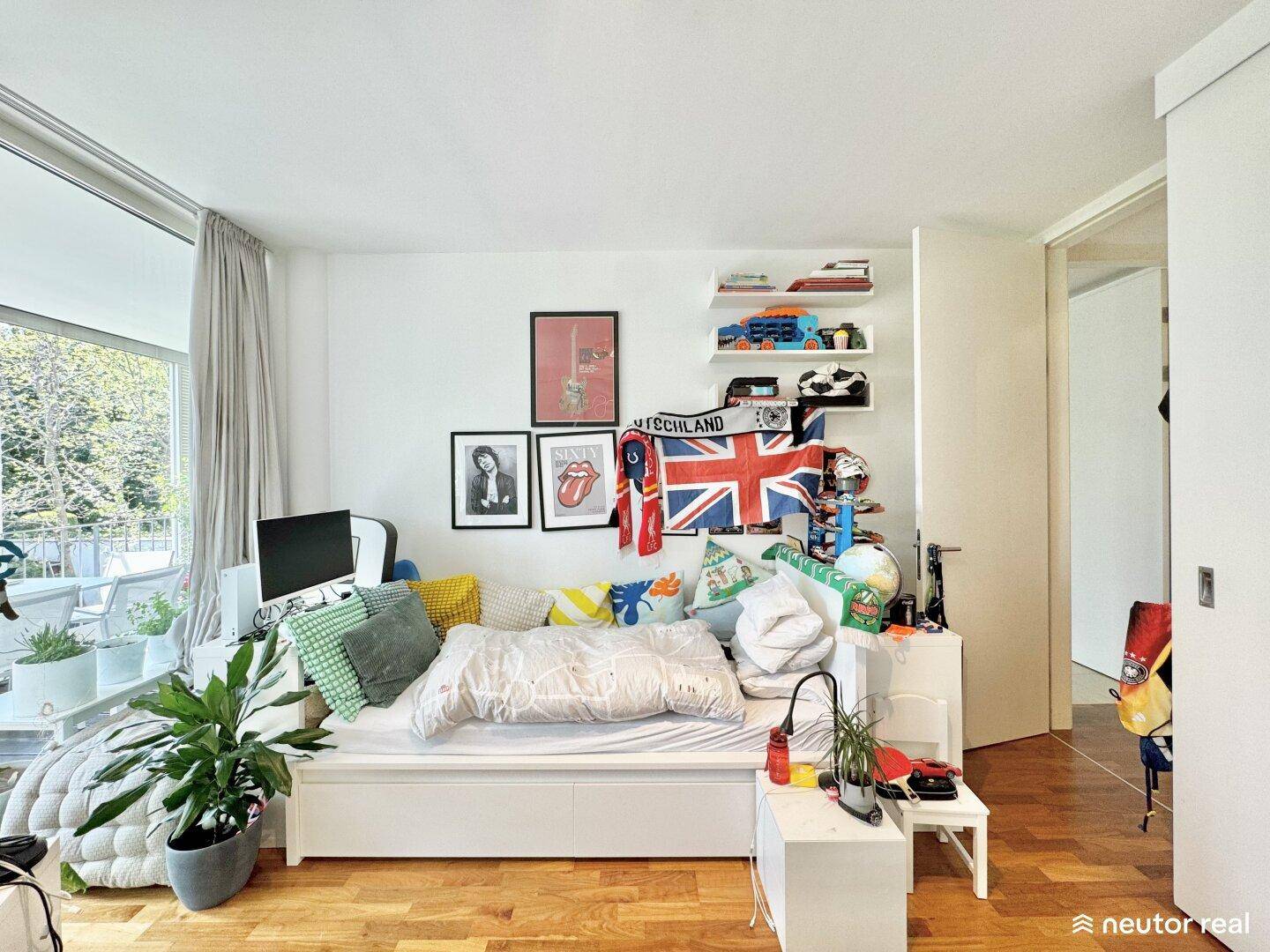 Kinderzimmer mit Bett, Schreibtisch und farbenfroher Dekoration, hell und freundlich.