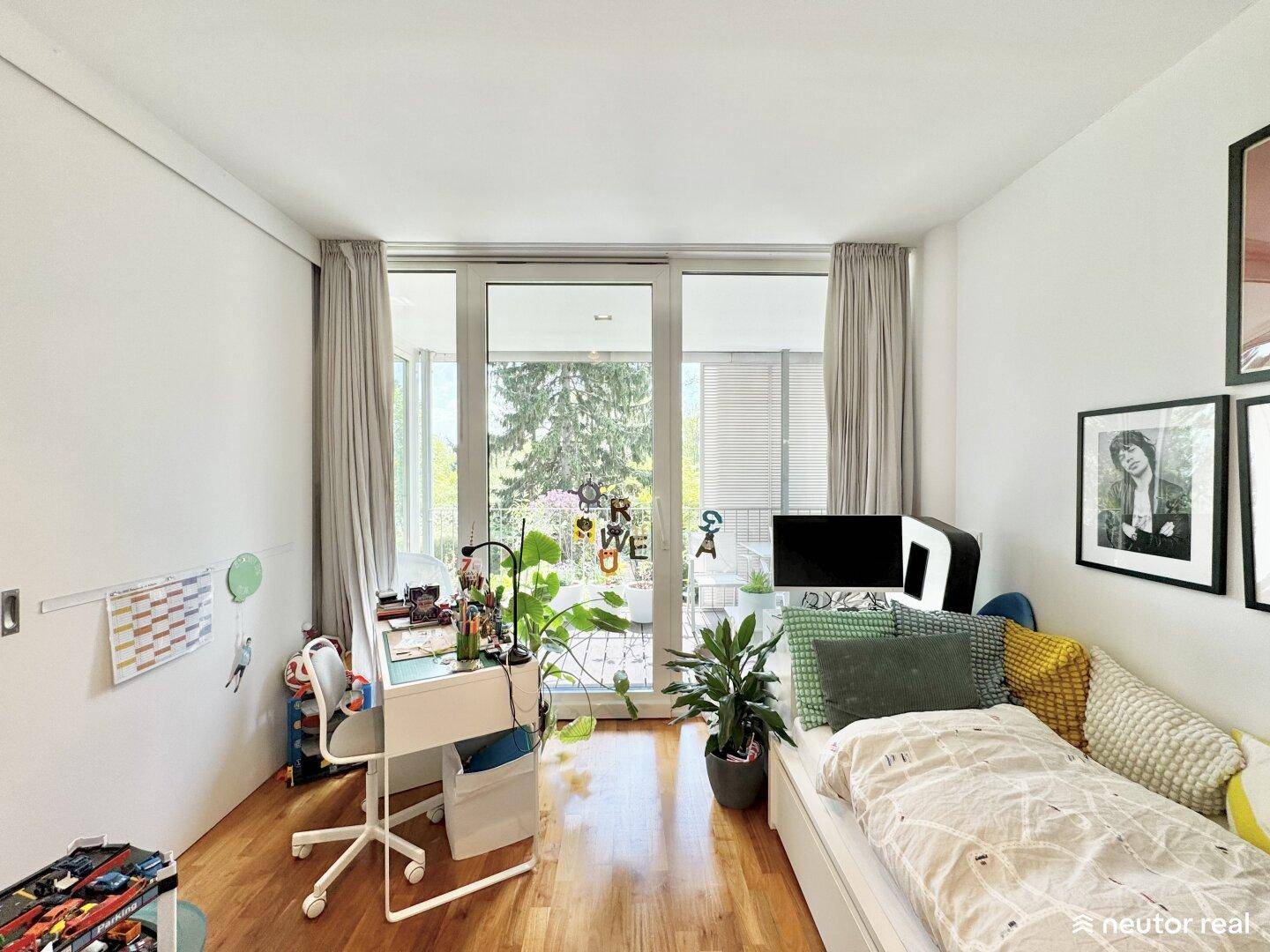 Helles Kinderzimmer mit Schreibtisch am Fenster und Zugang zum Balkon.