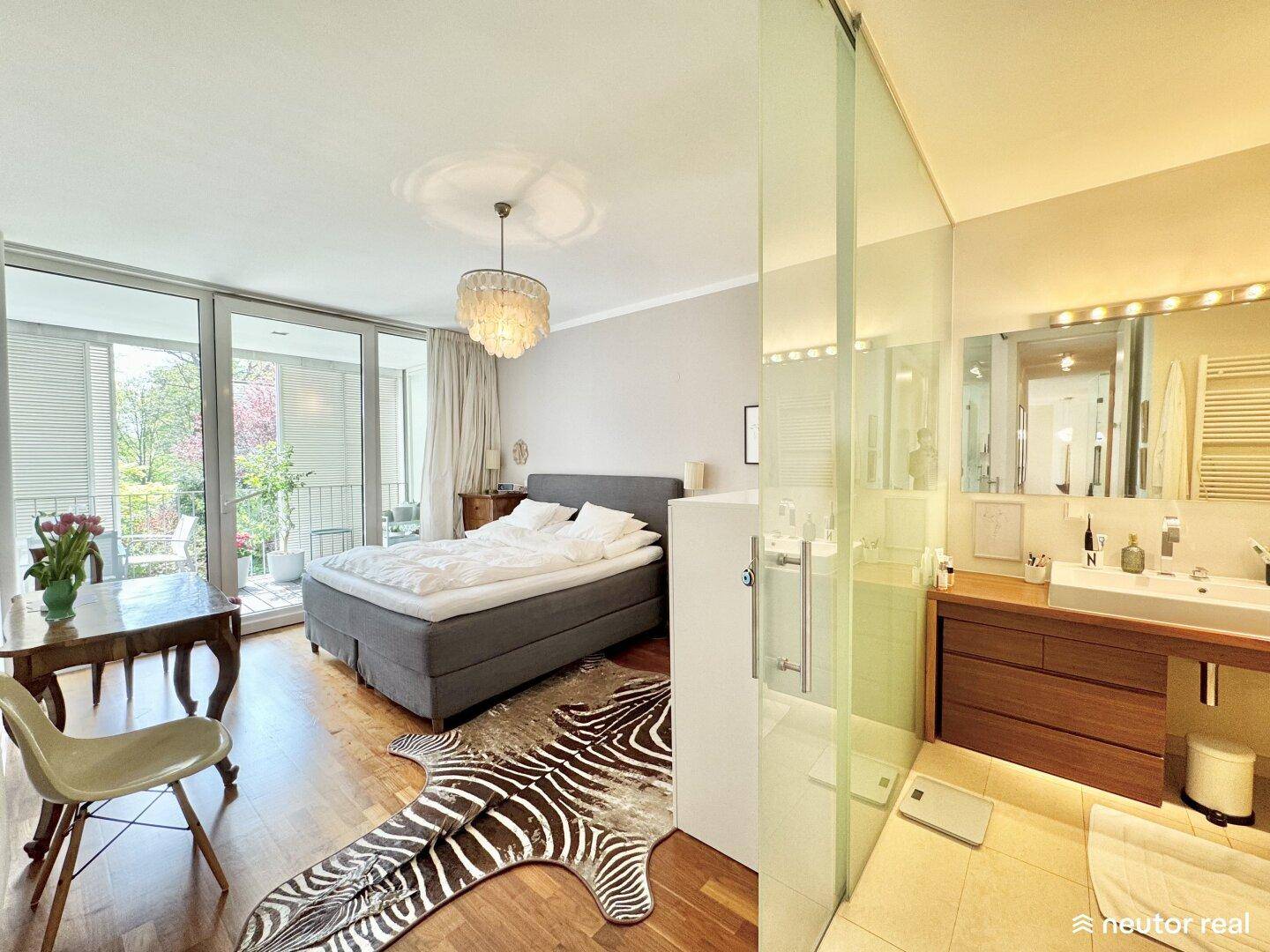 Schlafzimmer mit Doppelbett, Holzboden und direktem Zugang zum Balkon und Bad.