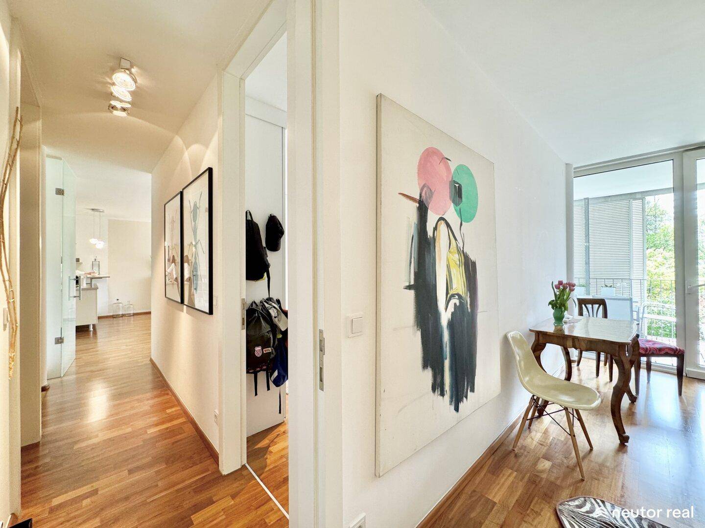 Langer Flur mit Holzboden und Kunstwerken, der verschiedene Wohnbereiche verbindet.