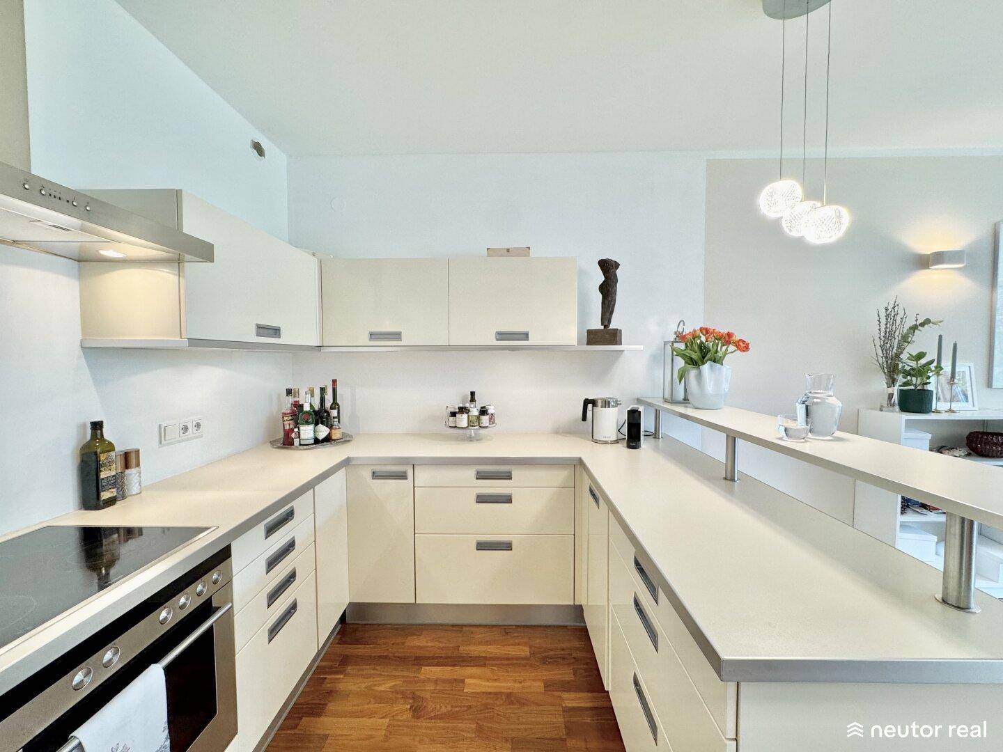 Moderne U-förmige Küche mit hellen Schränken, integrierten Geräten und viel Arbeitsfläche.