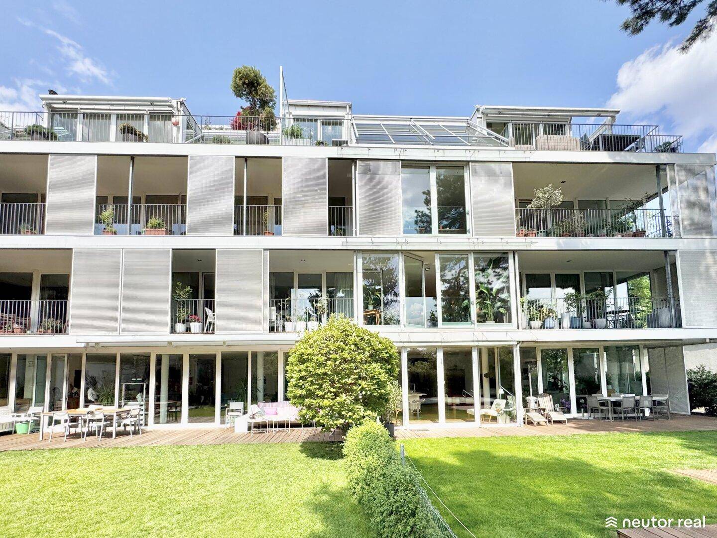 Moderne Wohnanlage mit großen Glasfronten, Balkonen, Terrassen und einem gepflegten Gartenbereich.