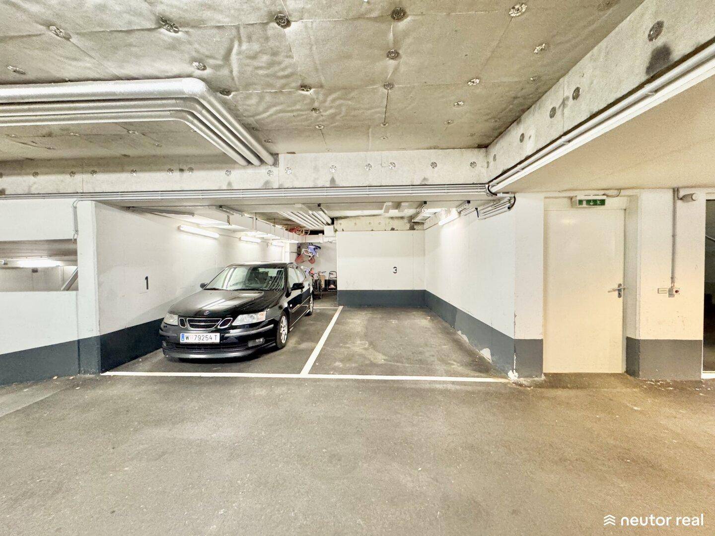 Tiefgaragenstellplatz mit Betonboden und einem geparkten Fahrzeug in einem Mehrfamilienhaus.