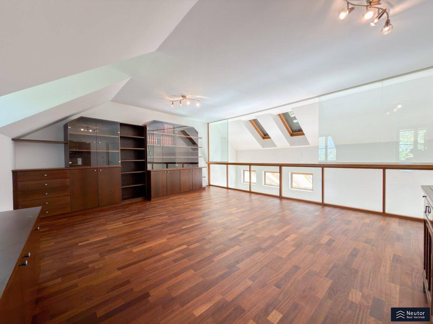 Geräumiger Dachbodenraum mit Holzboden, Einbauschränken und Dachfenstern, ideal als Büro.