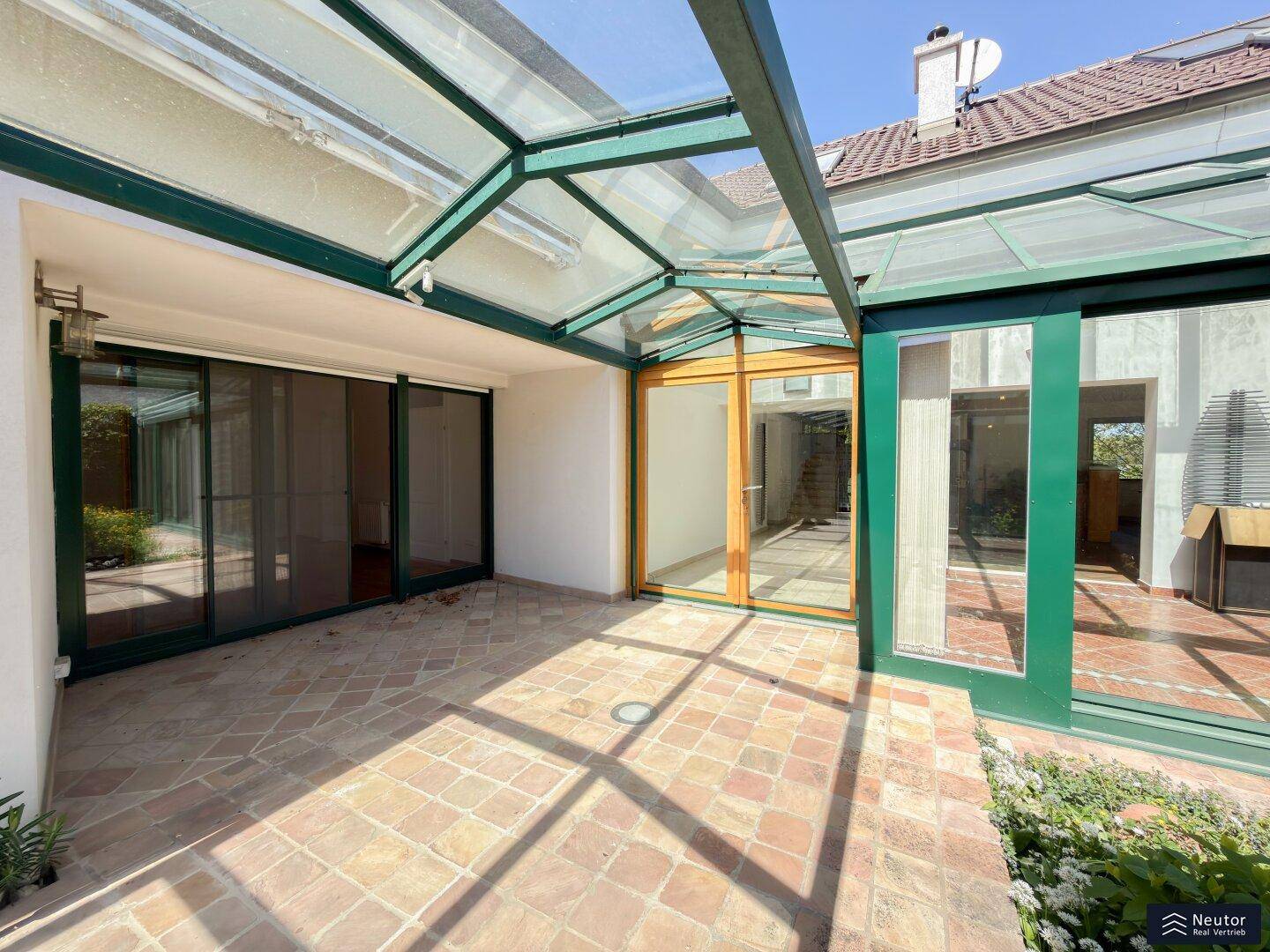 Geräumige Terrasse mit Terrakottafliesen und Glasüberdachung, direkt am Wintergarten gelegen.