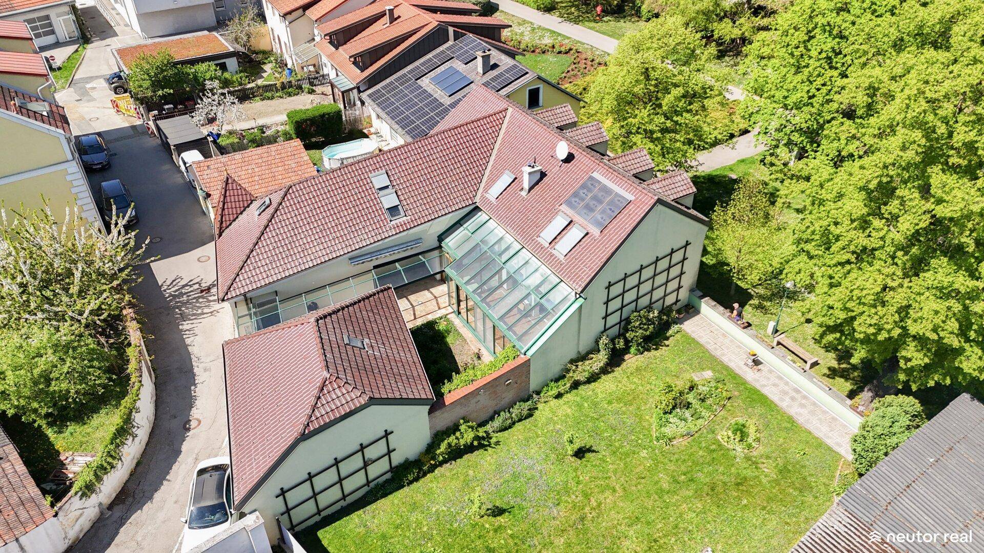 Luftaufnahme eines Anwesens mit mehreren Gebäuden, Garten und Solaranlagen auf den Dächern.