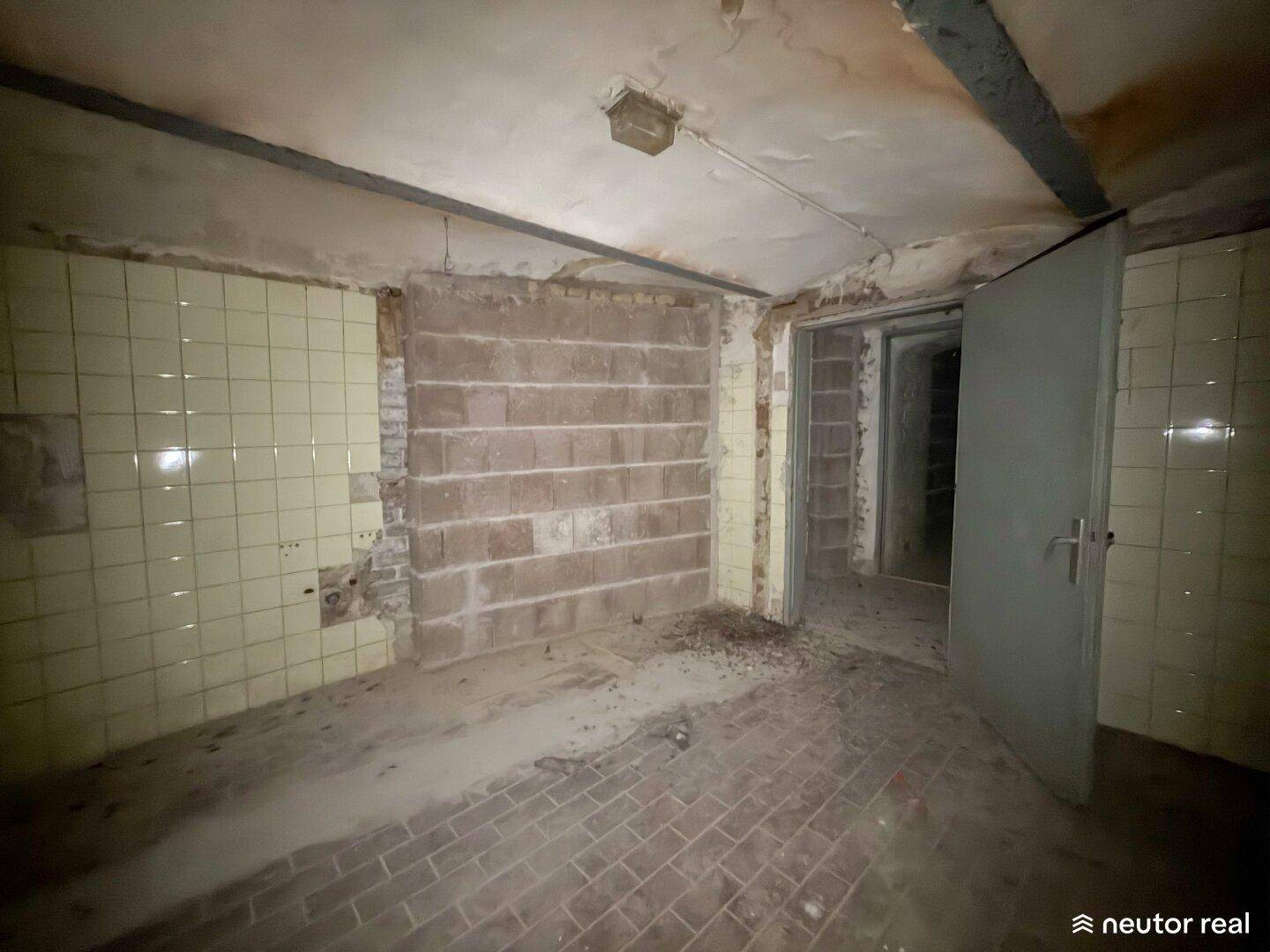 Kellerraum mit Ziegelboden und unverputzten Betonwänden, der einen rustikalen und funktionalen Eindruck vermittelt.