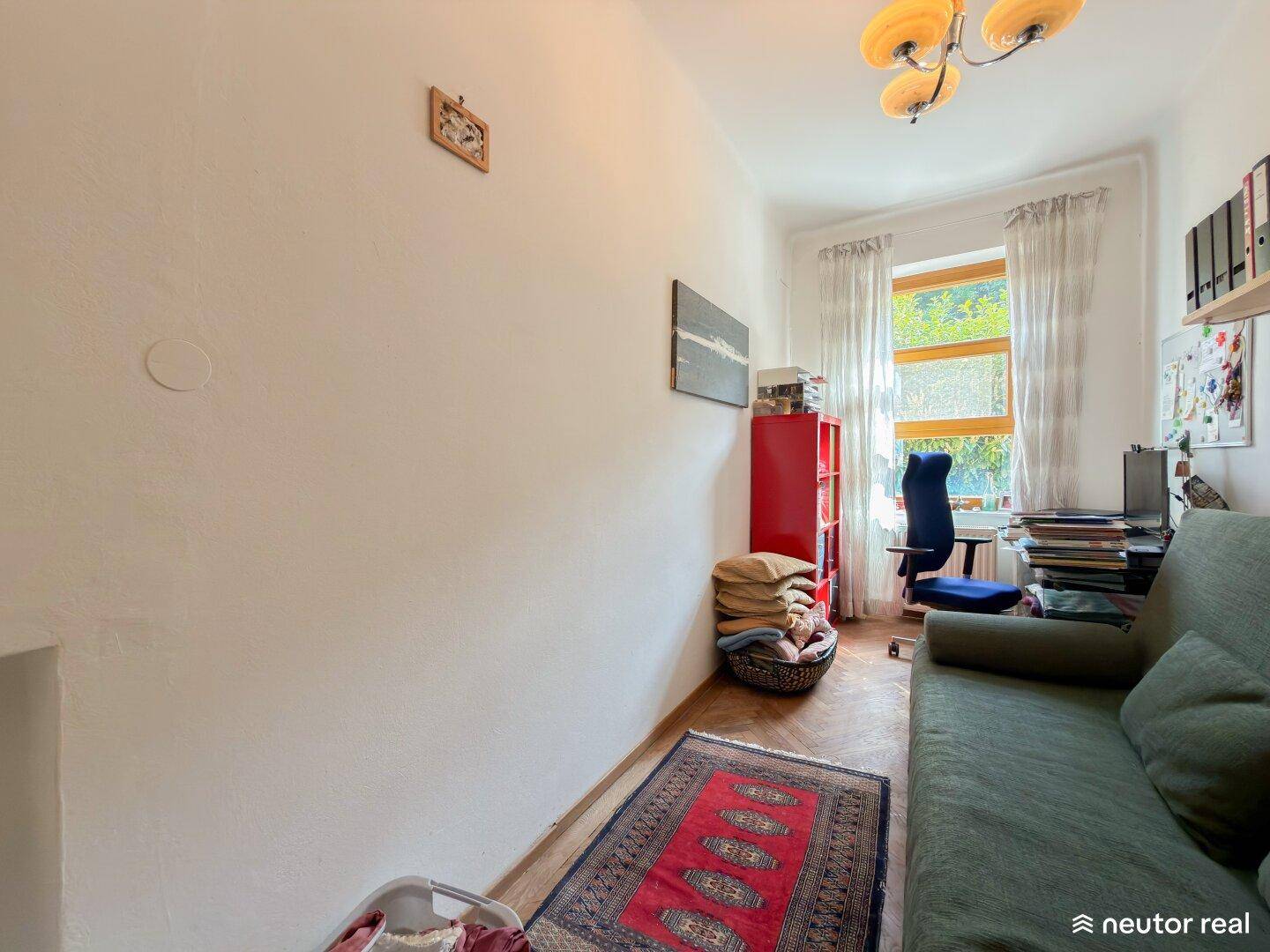 Kleines Zimmer mit Holzboden, Fenster und einfacher Einrichtung, ideal als Gästezimmer.