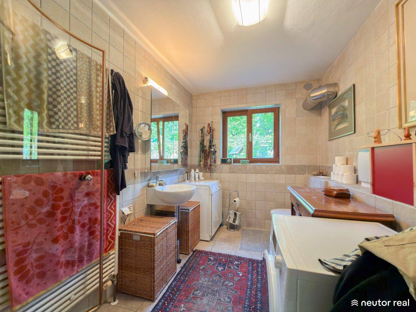 Helles Badezimmer mit Dusche, Waschmaschine, Fenster und beheiztem Handtuchhalter.