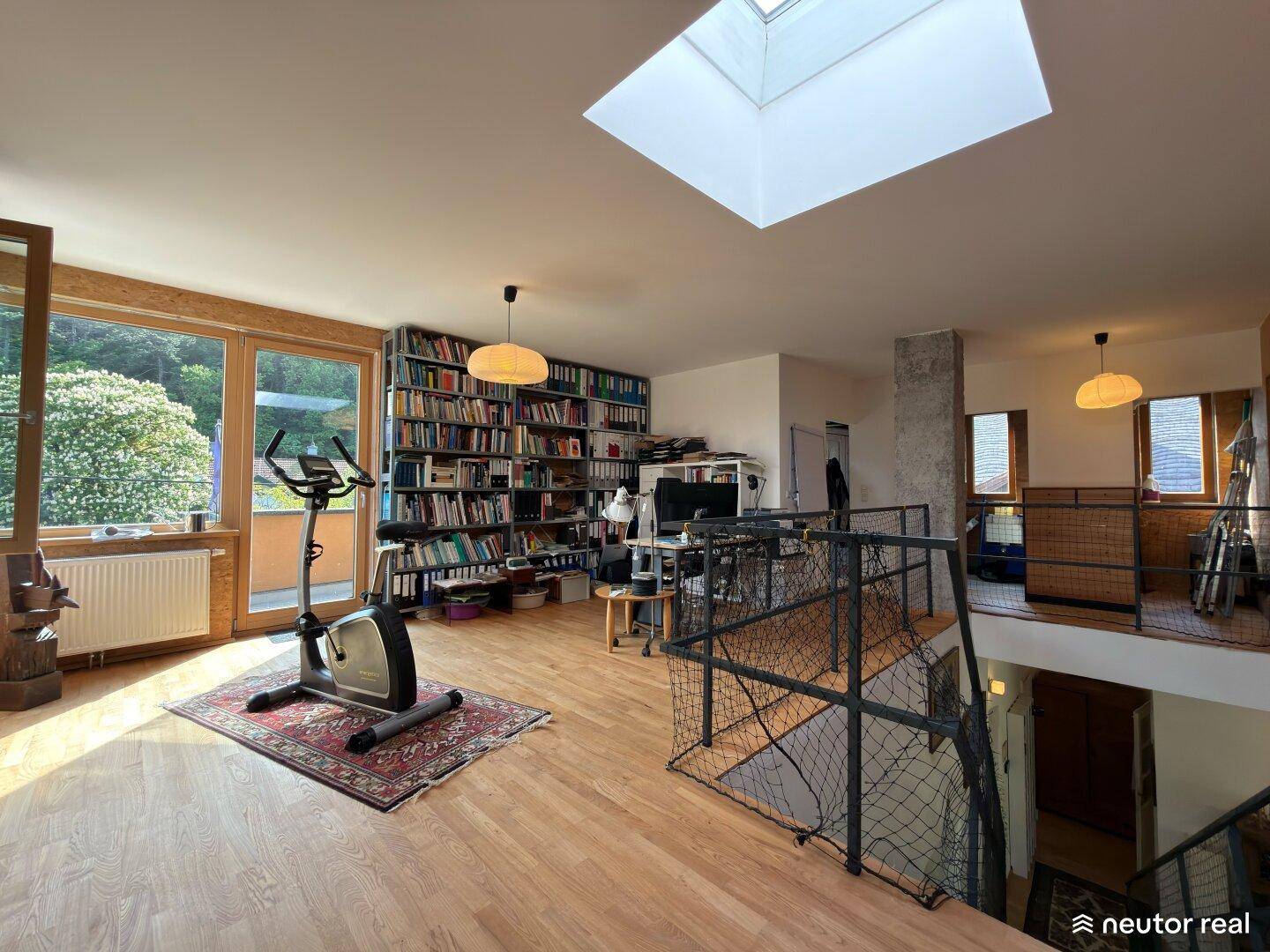 Helle Galerie mit Trainingsbereich, Bücherregalen und Oberlicht, die viel Tageslicht bietet.