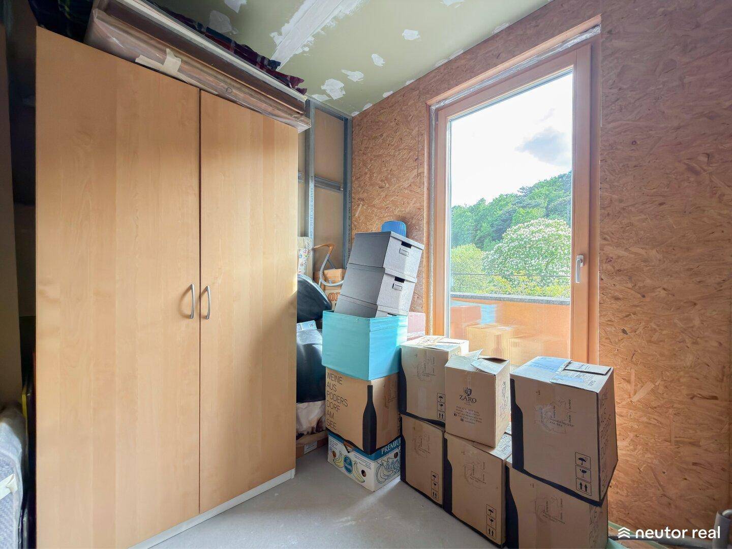 Abstellraum mit Schrank, Kartons und Fenster mit Blick ins Grüne.