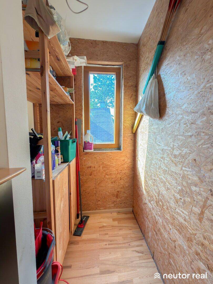Praktischer Hauswirtschaftsraum mit Regalen und Fenster für zusätzlichen Stauraum.