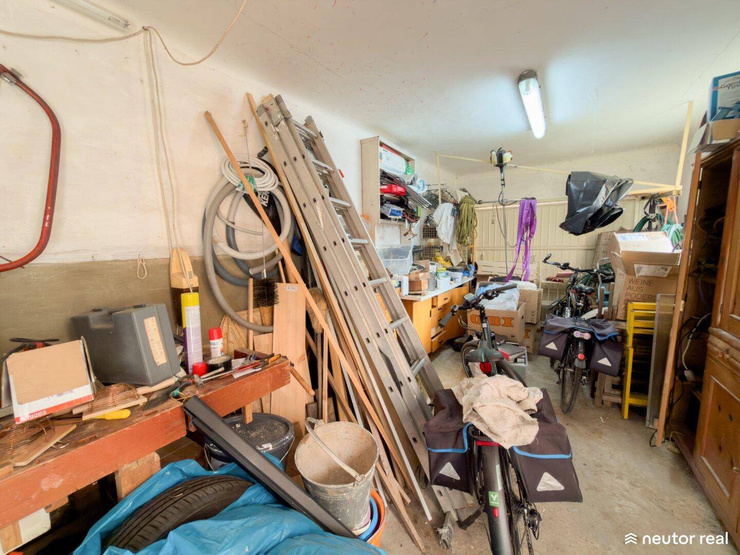 Geräumige Garage, die als Werkstatt und Abstellraum für Fahrräder und verschiedene Werkzeuge dient.