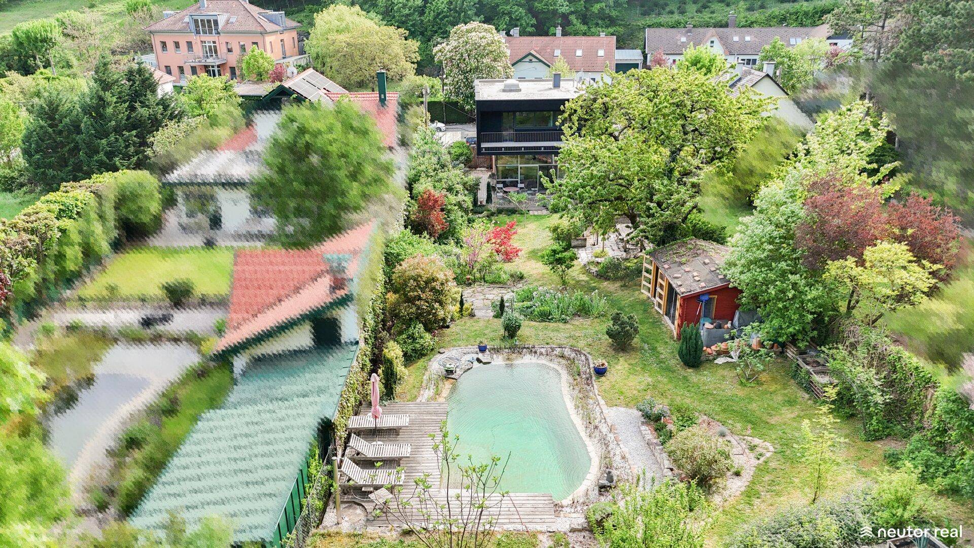 Luftaufnahme des Anwesens mit großem Garten, Schwimmteich und umliegender Wohnbebauung in grüner Umgebung.
