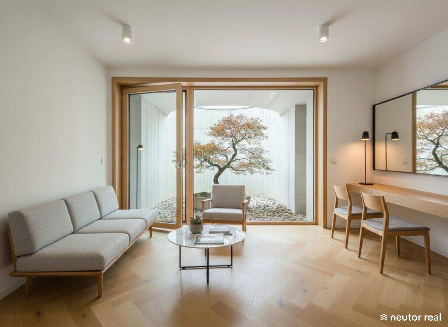 Gemütlicher Wohnbereich mit Sofa, Couchtisch und Blick auf einen begrünten Innenhof mit Baum.