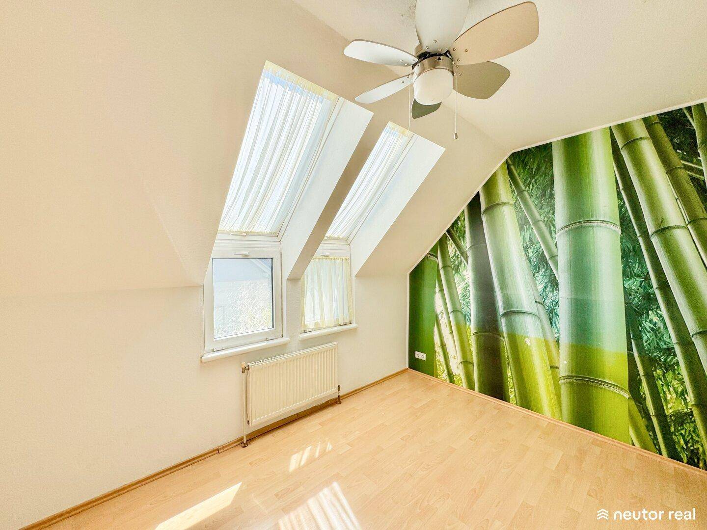 Schlafzimmer mit Holzparkett, Dachfenstern und einer dekorativen Bambus-Wandtapete.