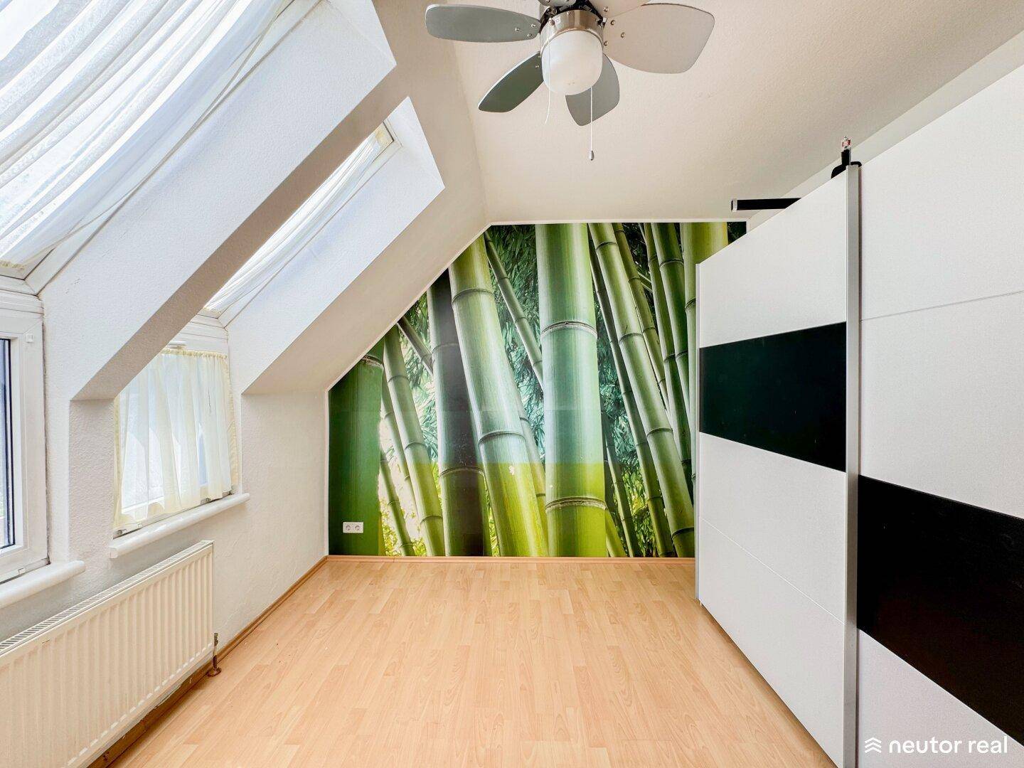 Schlafzimmer mit Holzparkett, Dachfenstern und großem Kleiderschrank mit Schiebetüren.