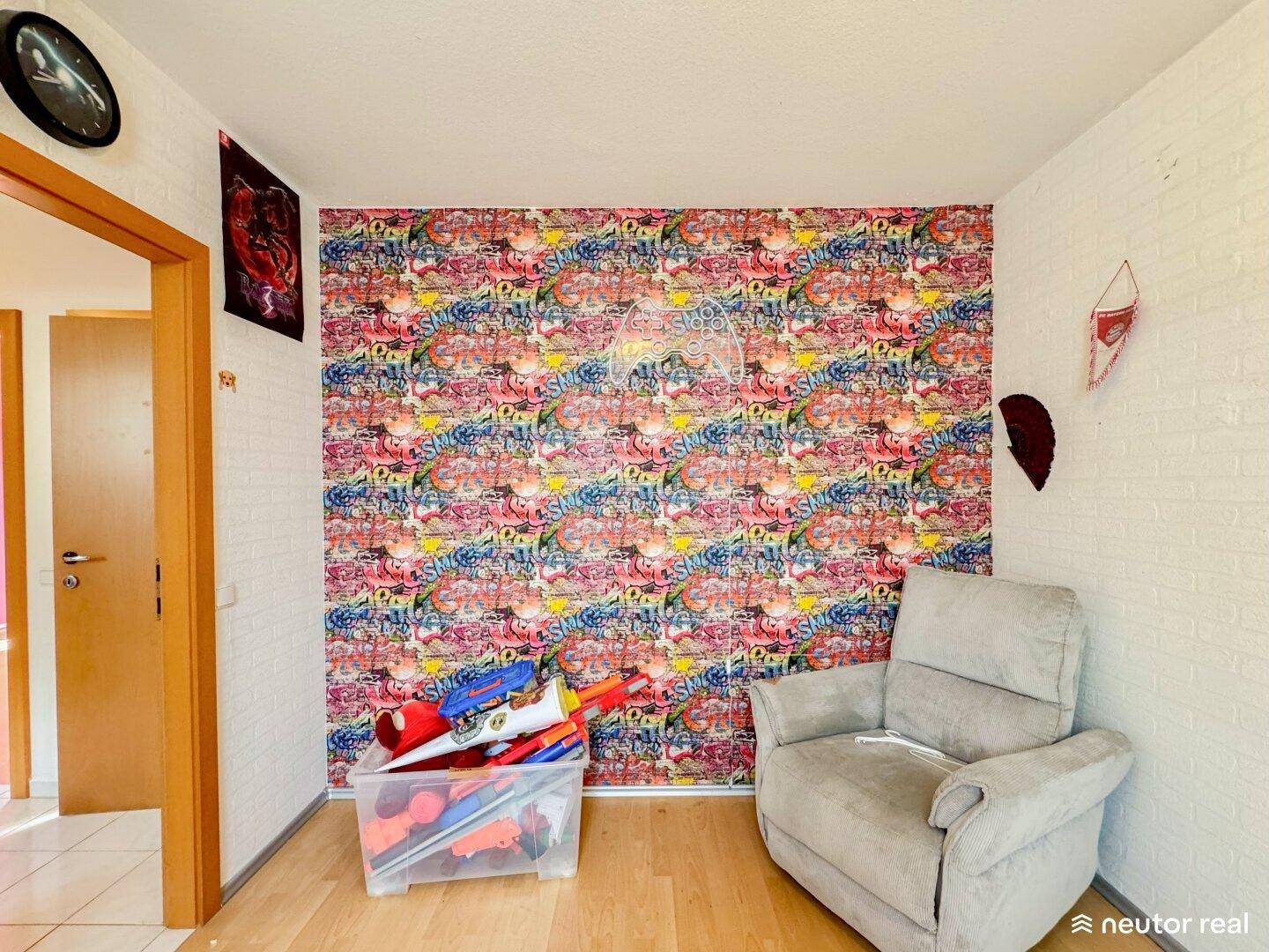 Zimmer mit auffälliger Graffiti-Tapete, weißer Ziegelwandoptik und einem bequemen Sessel.