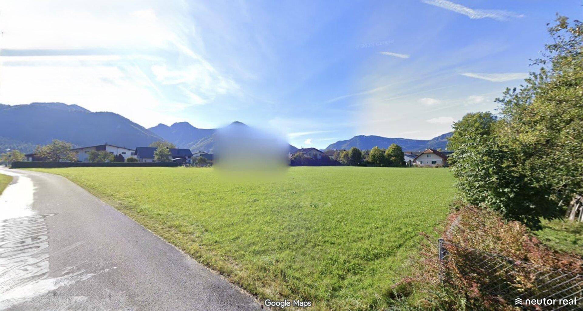 Idyllische Landschaft mit ausgedehnter grüner Wiese und majestätischen Bergen am Horizont.