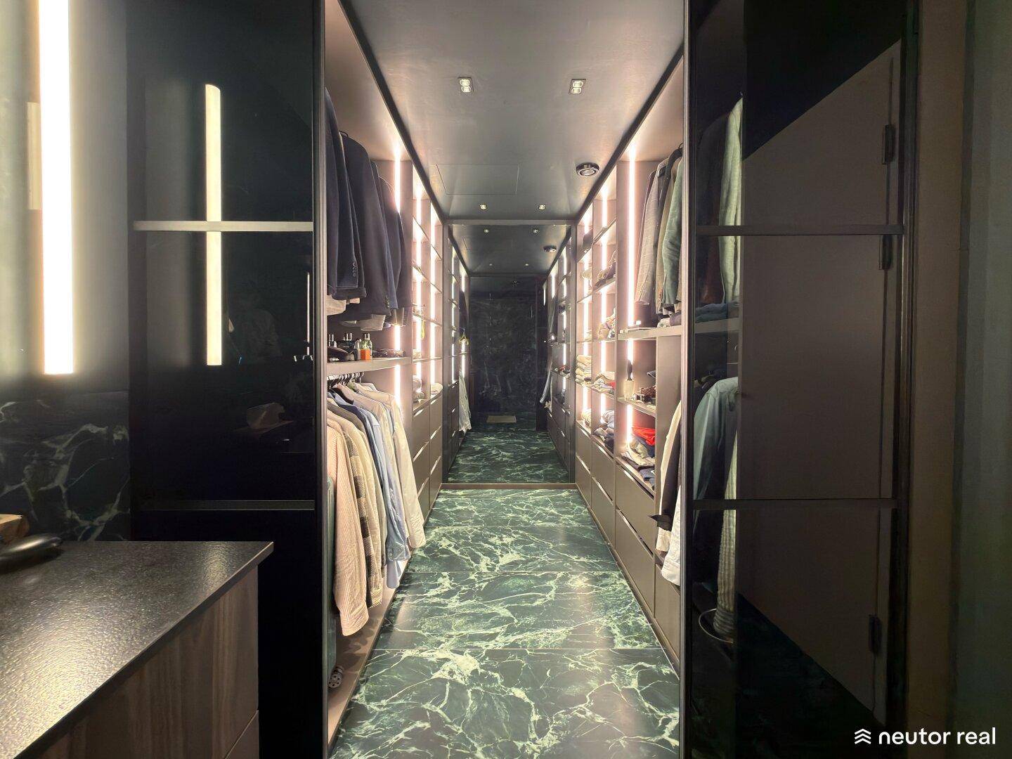 Geräumiger begehbarer Kleiderschrank mit integrierten Regalen und dunklem Marmorboden.