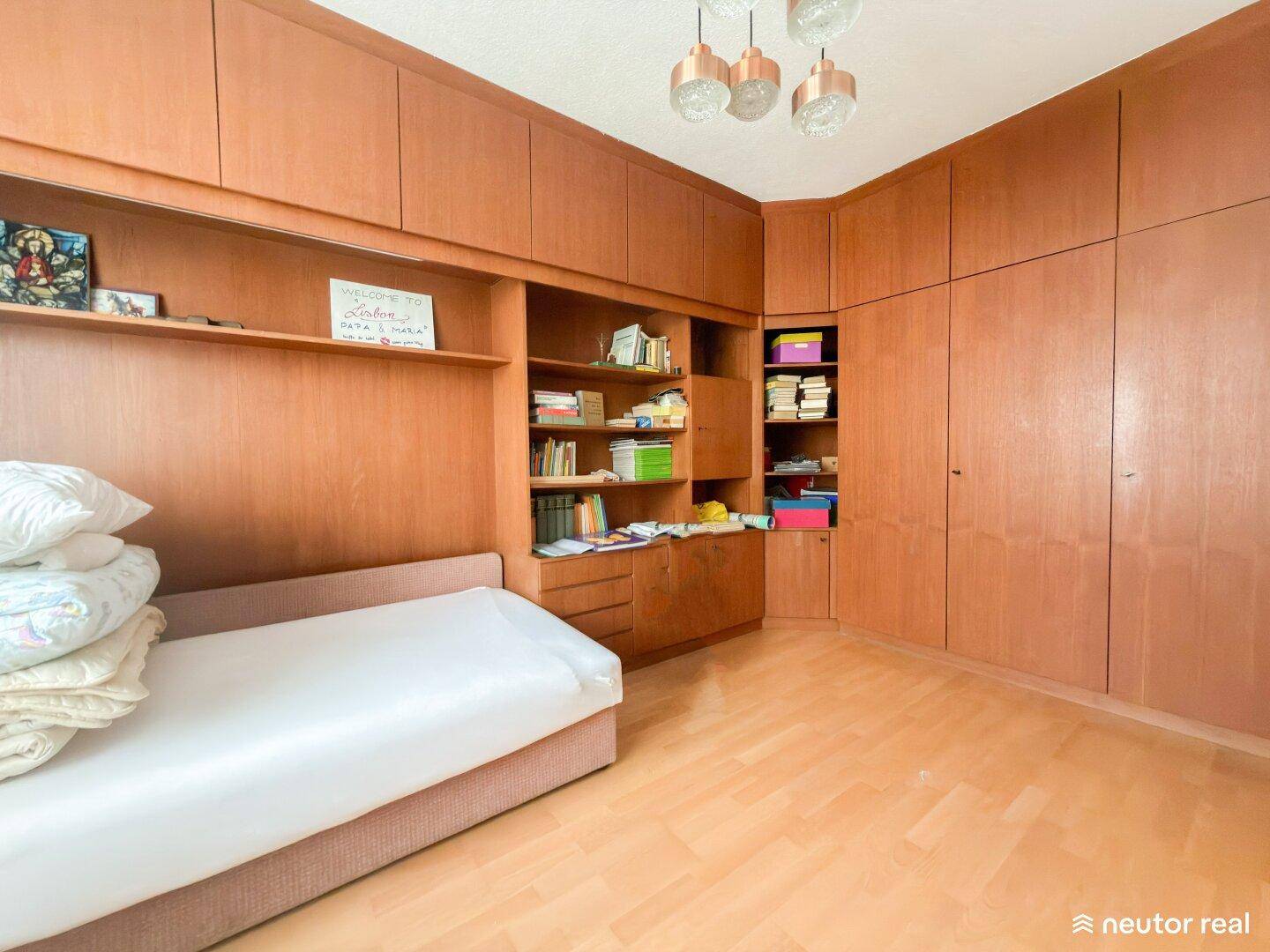 Schlafzimmer mit umfangreichen Holz-Einbauschränken und hellem Holzboden.