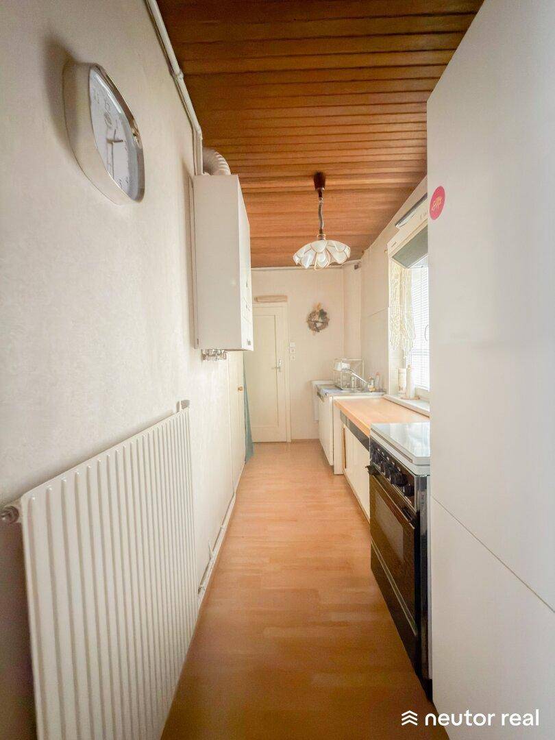 Schmale Küche mit Holzdecke, Gastherme und Fenster für natürliches Licht.