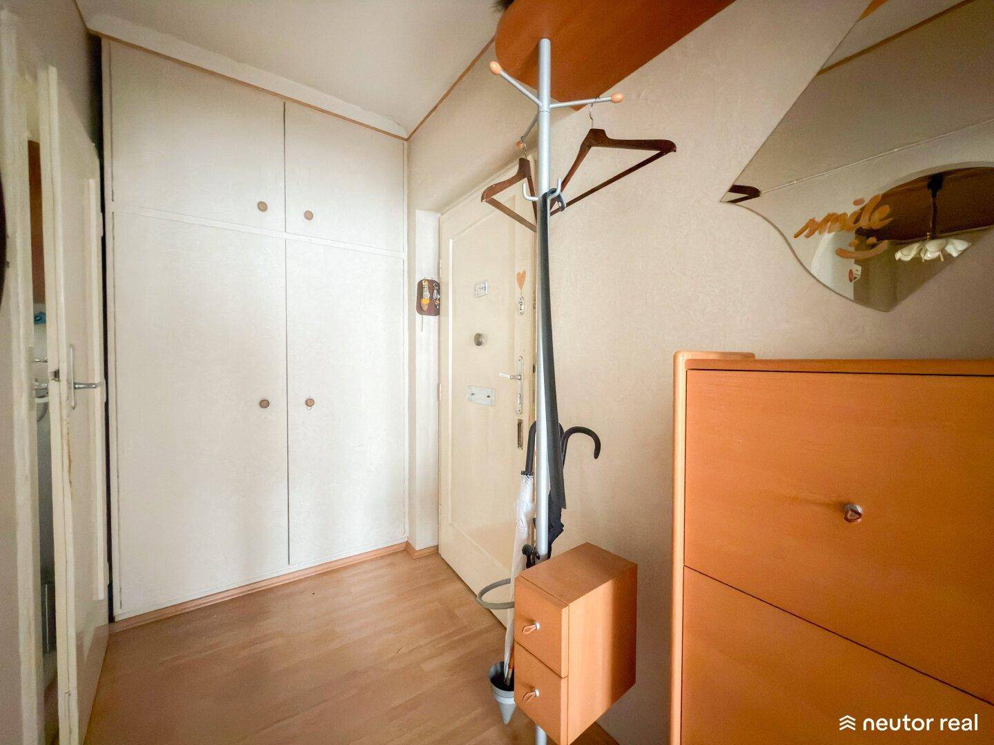 Eingangsbereich mit Einbauschränken, Garderobe und hellem Holzboden.