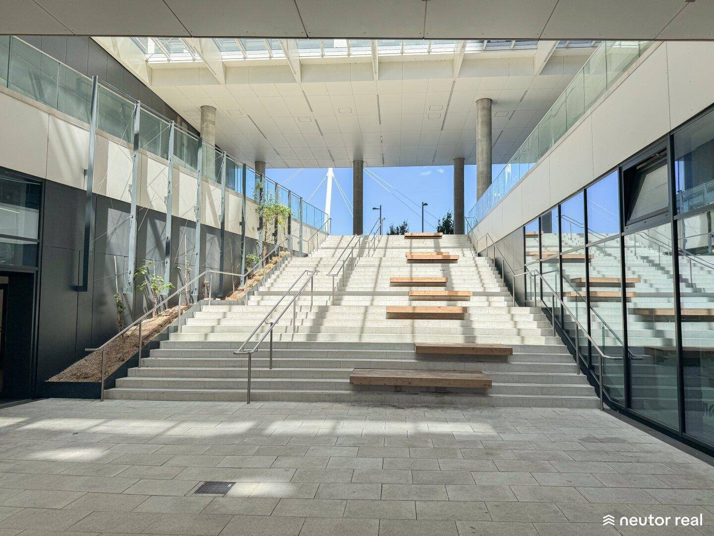 Moderne Außentreppe mit Sitzgelegenheiten in einem offenen Gebäudekomplex.