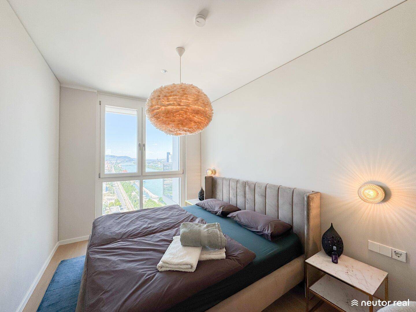 Modernes Schlafzimmer mit Doppelbett, Holzboden und weitem Blick auf die Stadt und den Fluss.