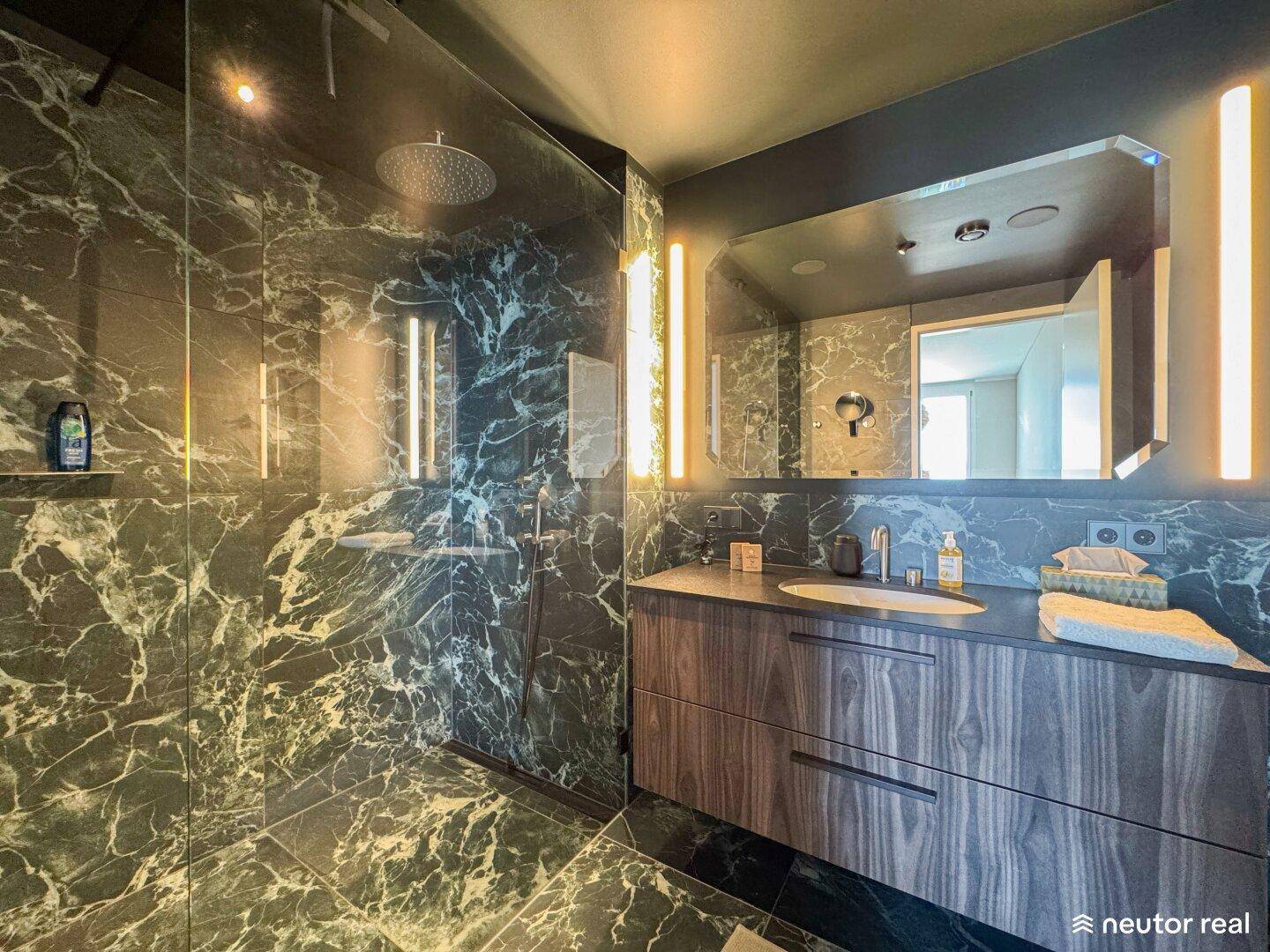 Modernes Badezimmer mit dunklen Marmorfliesen, Regendusche und elegantem Waschtisch.