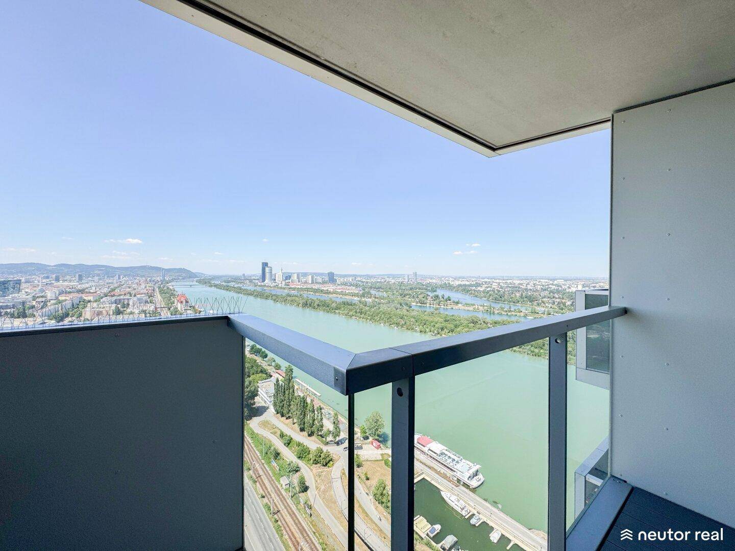 Geräumiger Balkon mit Glasgeländer und atemberaubendem Blick auf die Stadt und den Fluss.