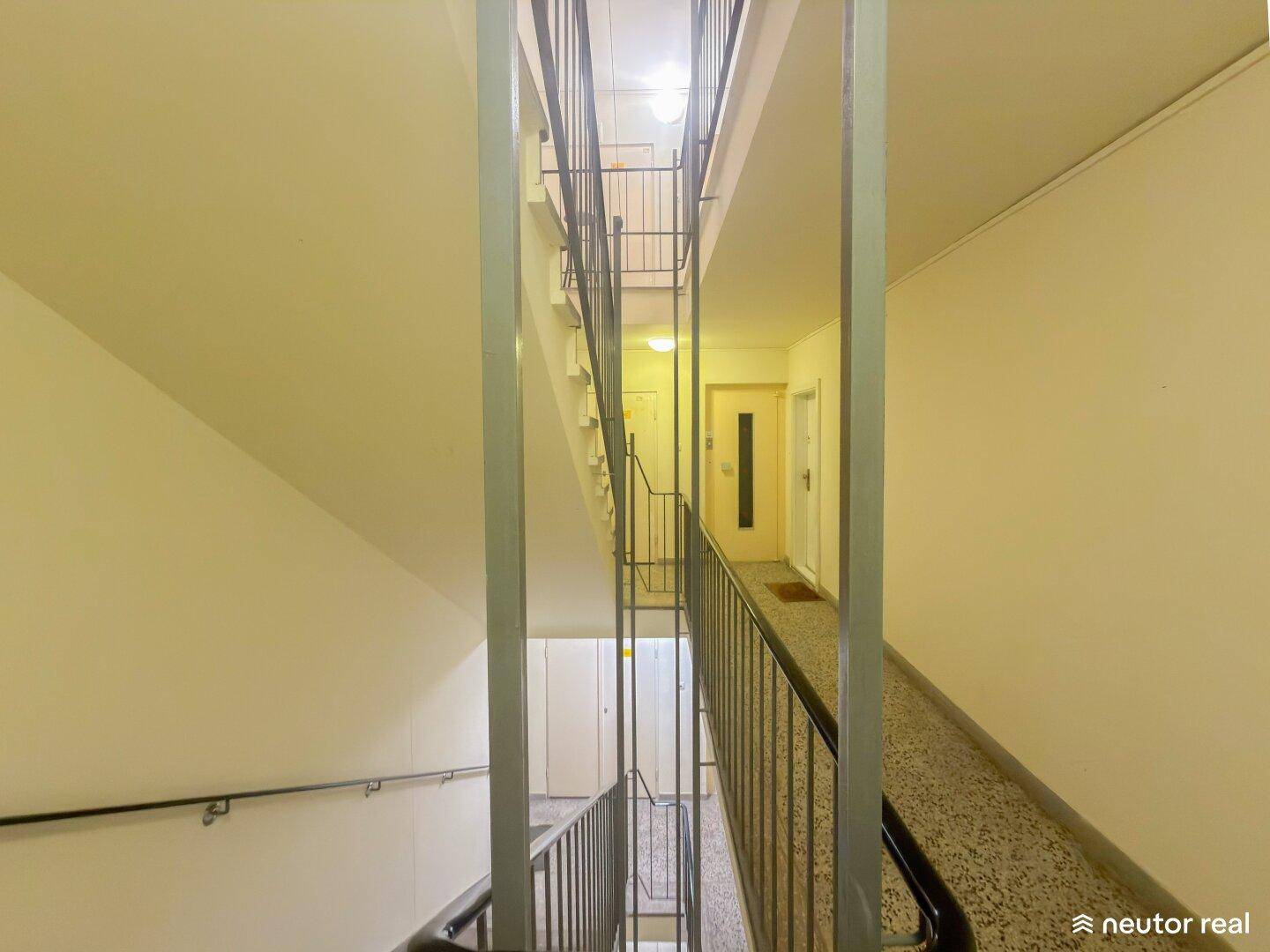 Blick nach oben im Treppenhaus mit mehreren Etagen und schlichtem Design.