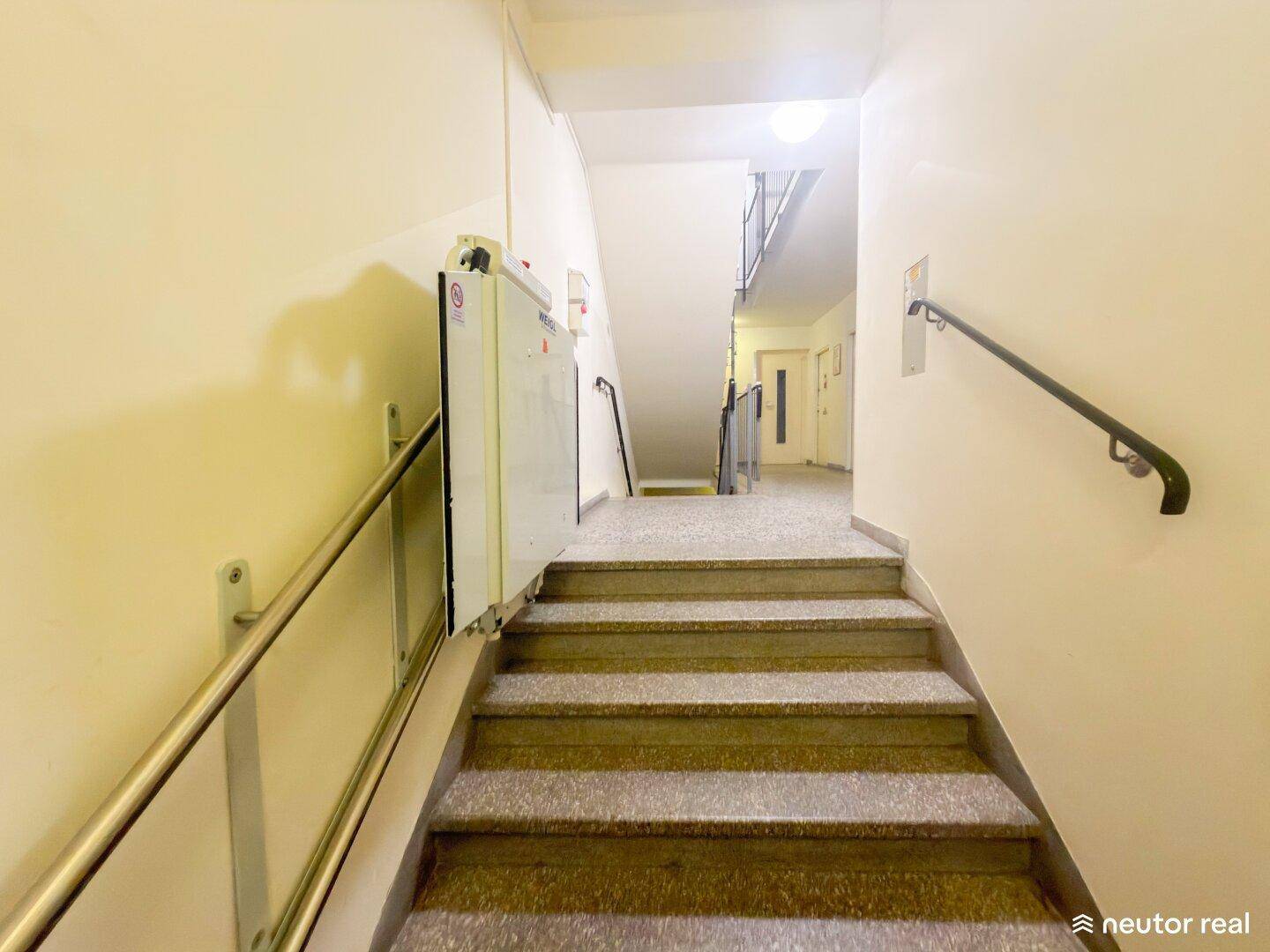 Treppenhaus mit Treppenlift für Barrierefreiheit und Handlauf.