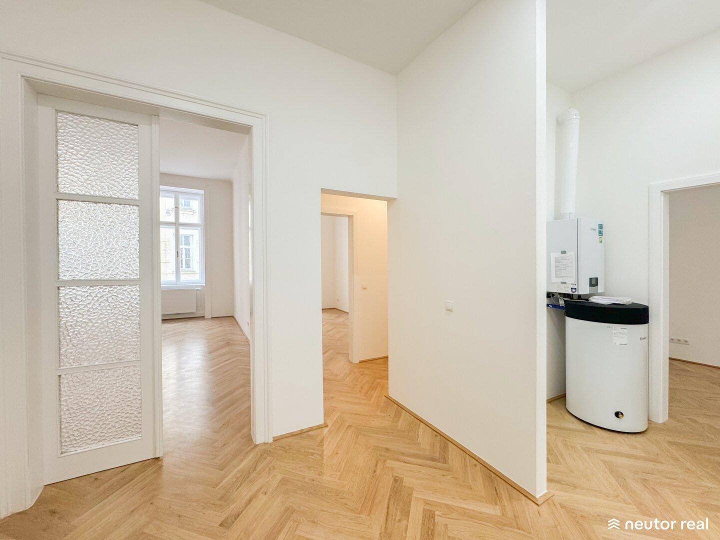 Heller Flur mit Heizungsanlage und Zugang zu weiteren Räumen, ausgestattet mit Parkettboden.