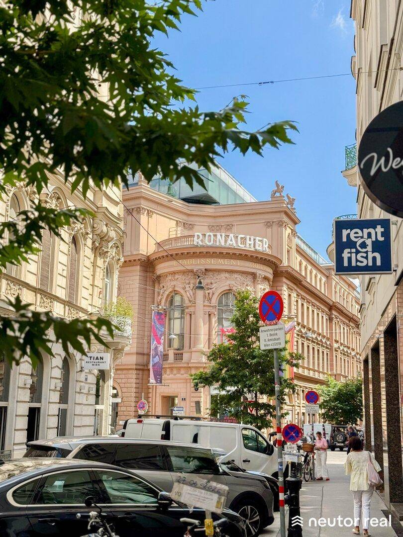 Historisches Gebäude an einer belebten Straße mit Geschäften und Passanten.
