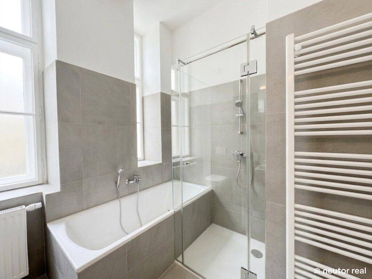 Modernes Badezimmer mit Badewanne, Glasdusche und beheiztem Handtuchhalter.