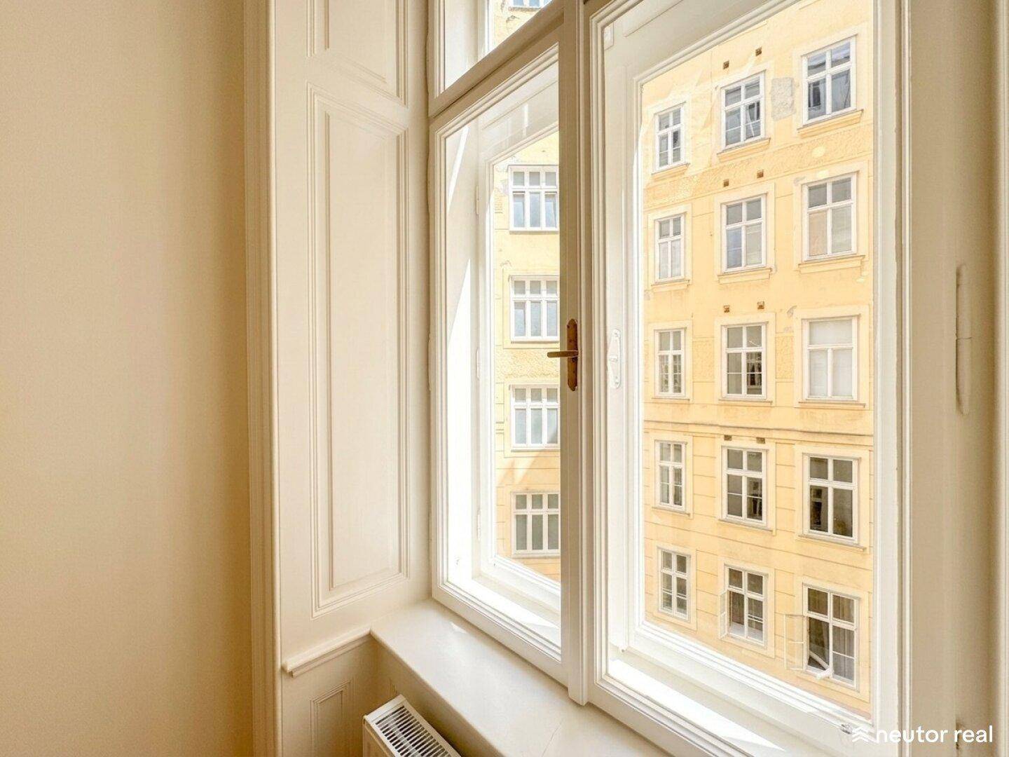 Großes Fenster mit Blick auf die gegenüberliegende Fassade, das viel Licht hereinlässt.